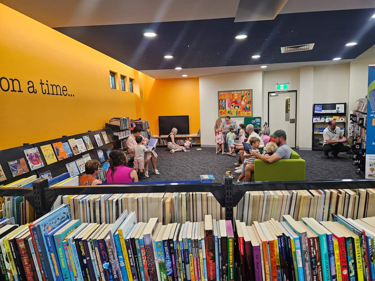 A group of children and adults reading in a library.