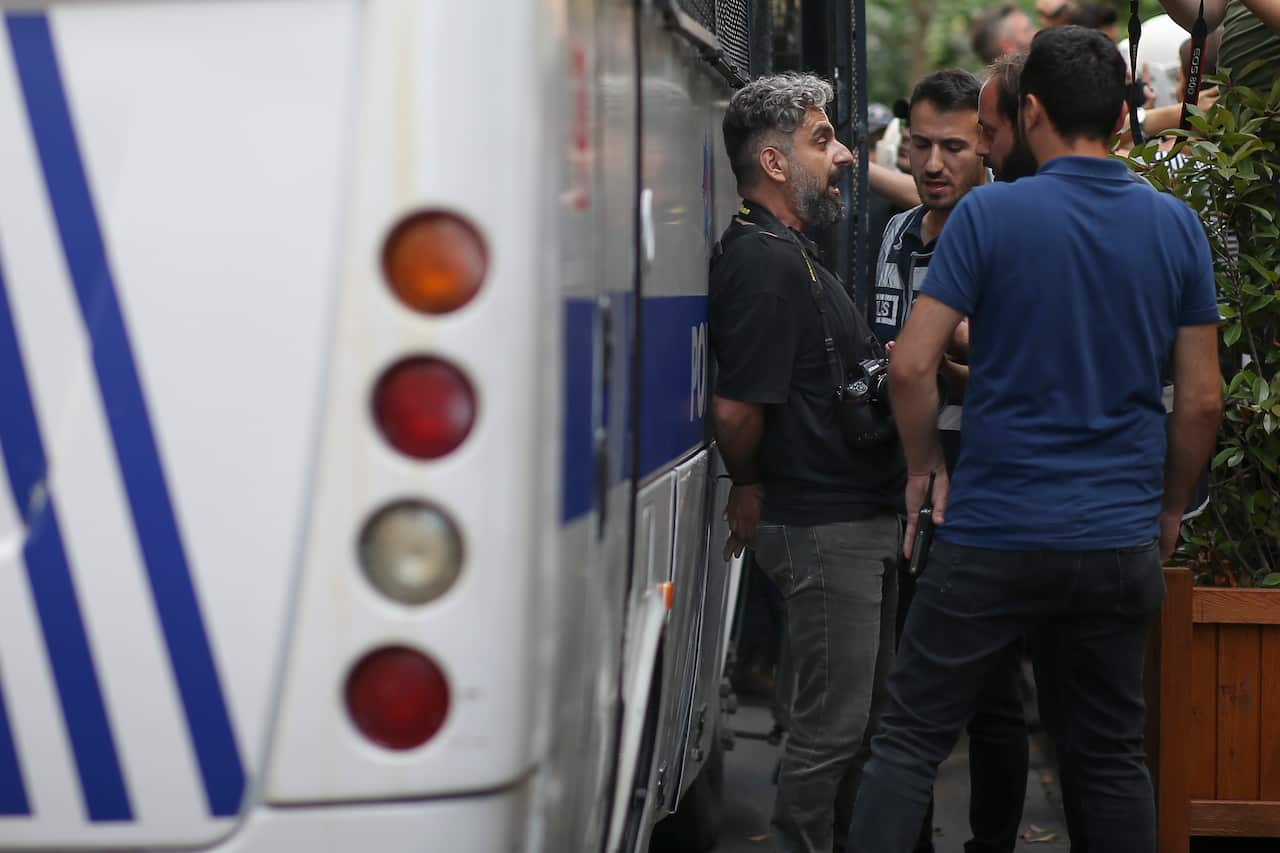 Turkish photographer Bulent Kilic standing against a police van with officers