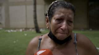 A close up of woman with a medical mask under her chin who has been crying.