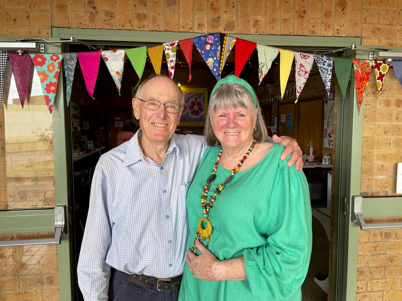 A man in a collared shirt and a woman in a green blouse.