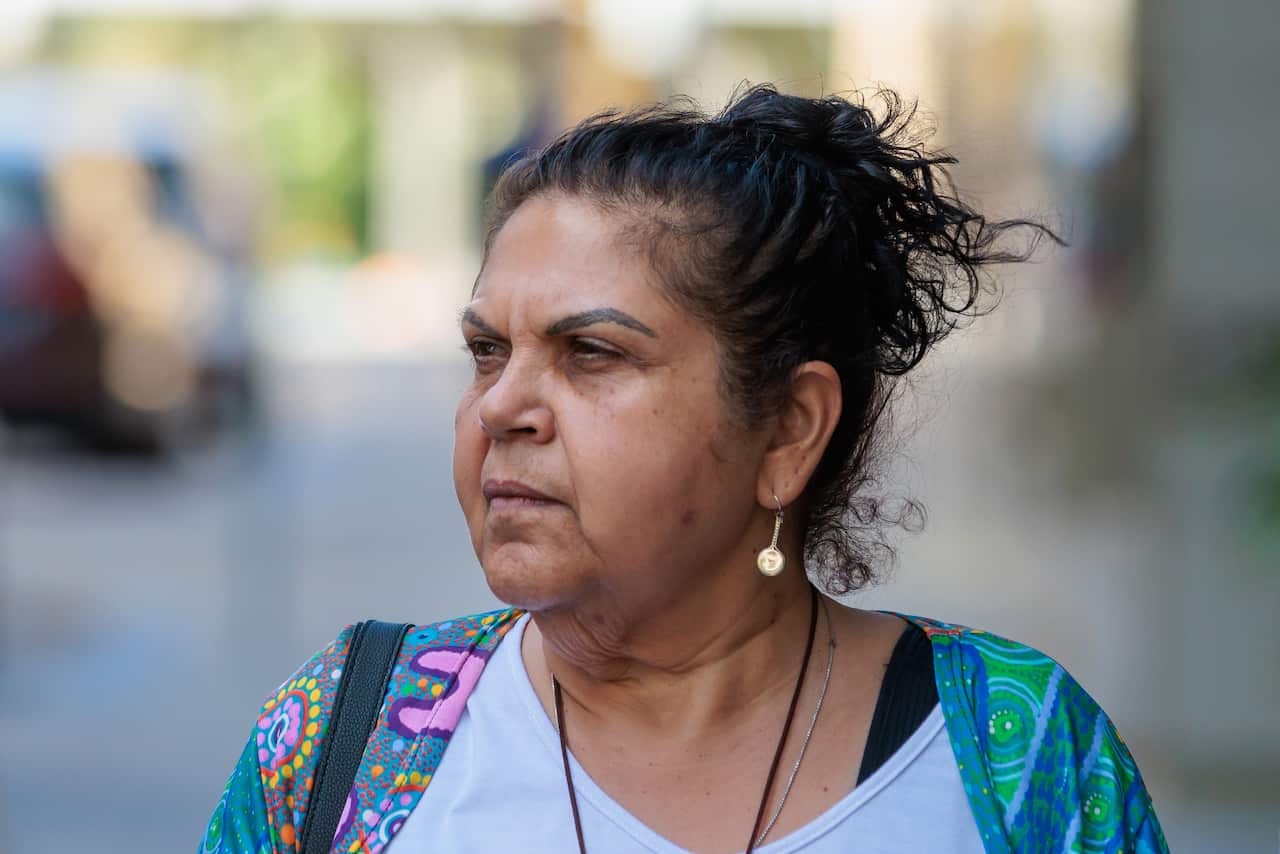 A woman with brown hair wearing a colourful cardigan