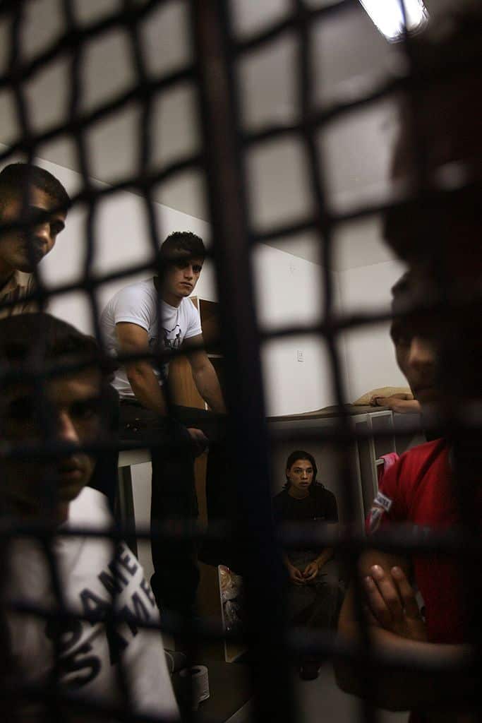 A black grate door with faces looking out from behind it.