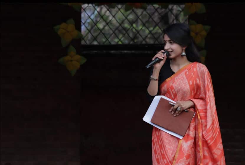 A woman in a red dress speaking into a microphone. 