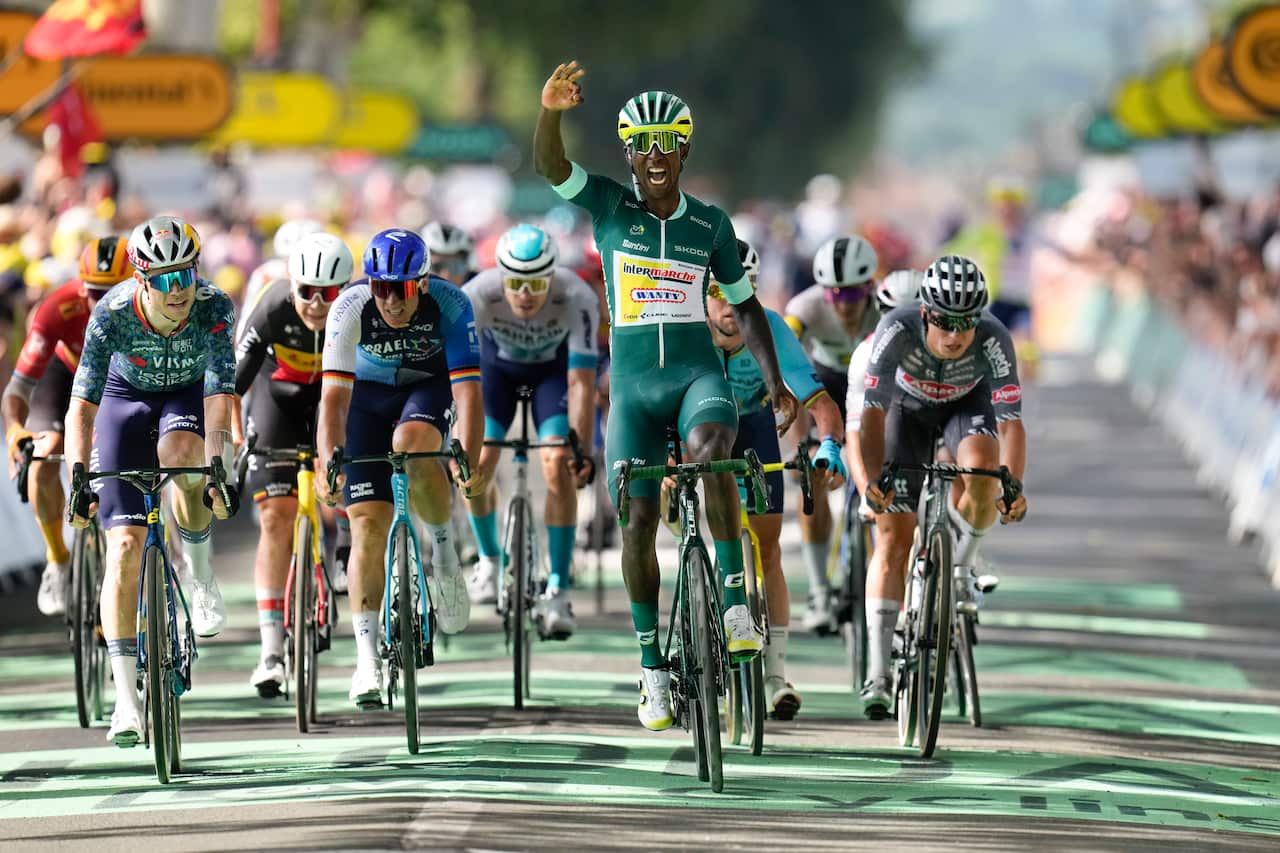 A man in a green jersey leads a large pack of cyclists.