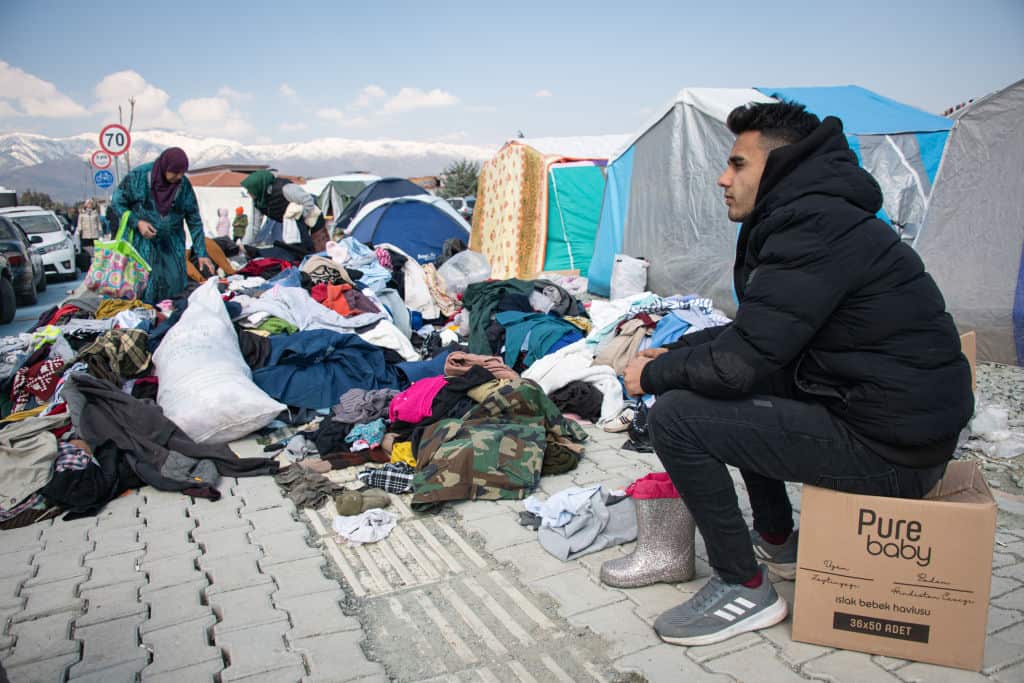 Displaced residents of Antakya in southern Türkiye search through donated clothes near an emergency tent shelter camp.