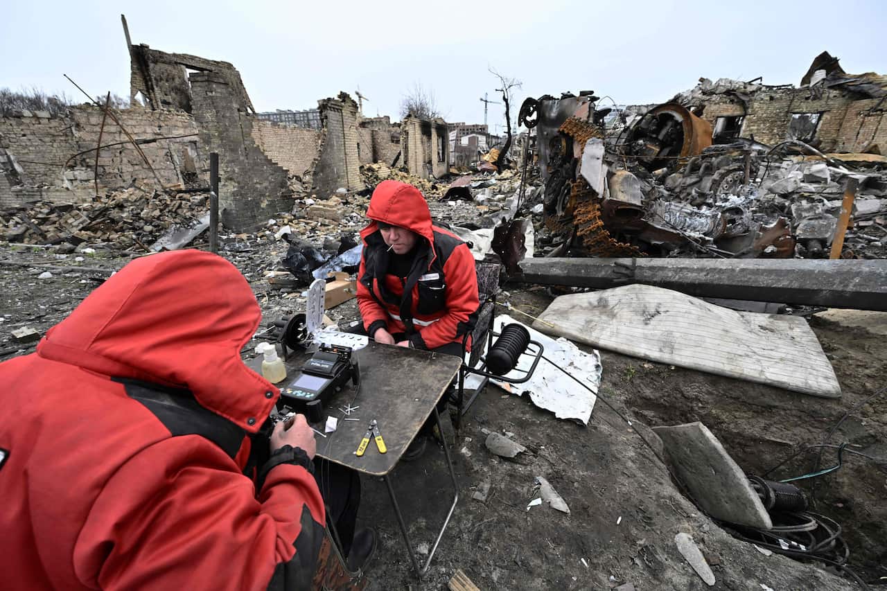 Repairmen restore local communication cables among the debris of destroyed armoured vehicles and buildings on a street in the town of Bucha, on the outskirts of the Ukrainian capital Kyiv.