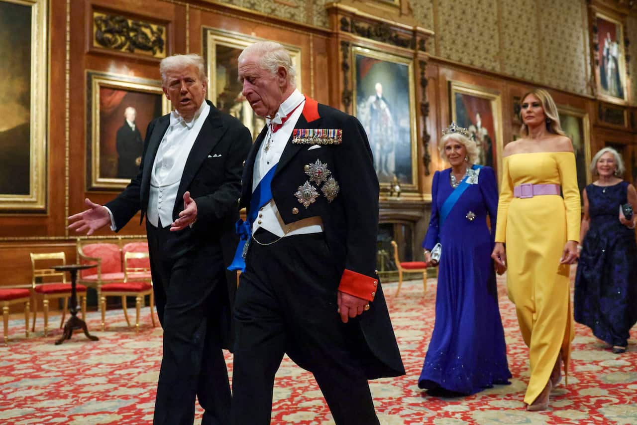 Donald Trump walking down a gilded hall alongside King Charles, talking and gesticulating.