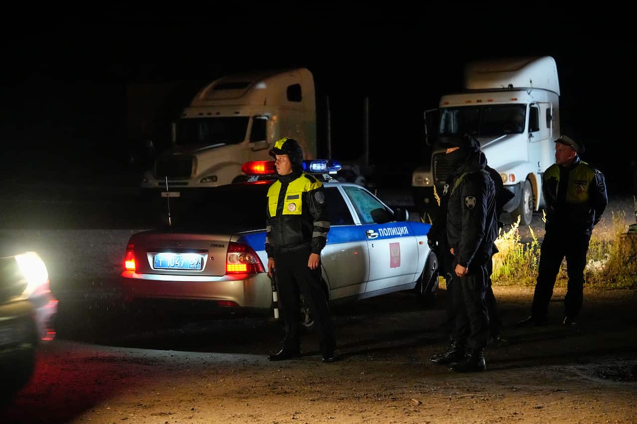 Police officers standing next to a police car.