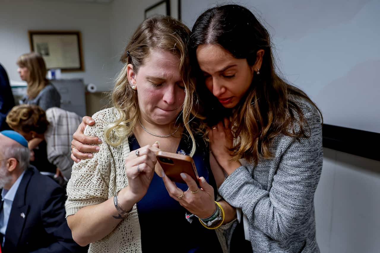 Two women looking at a phone screen. They are visibly distraught.