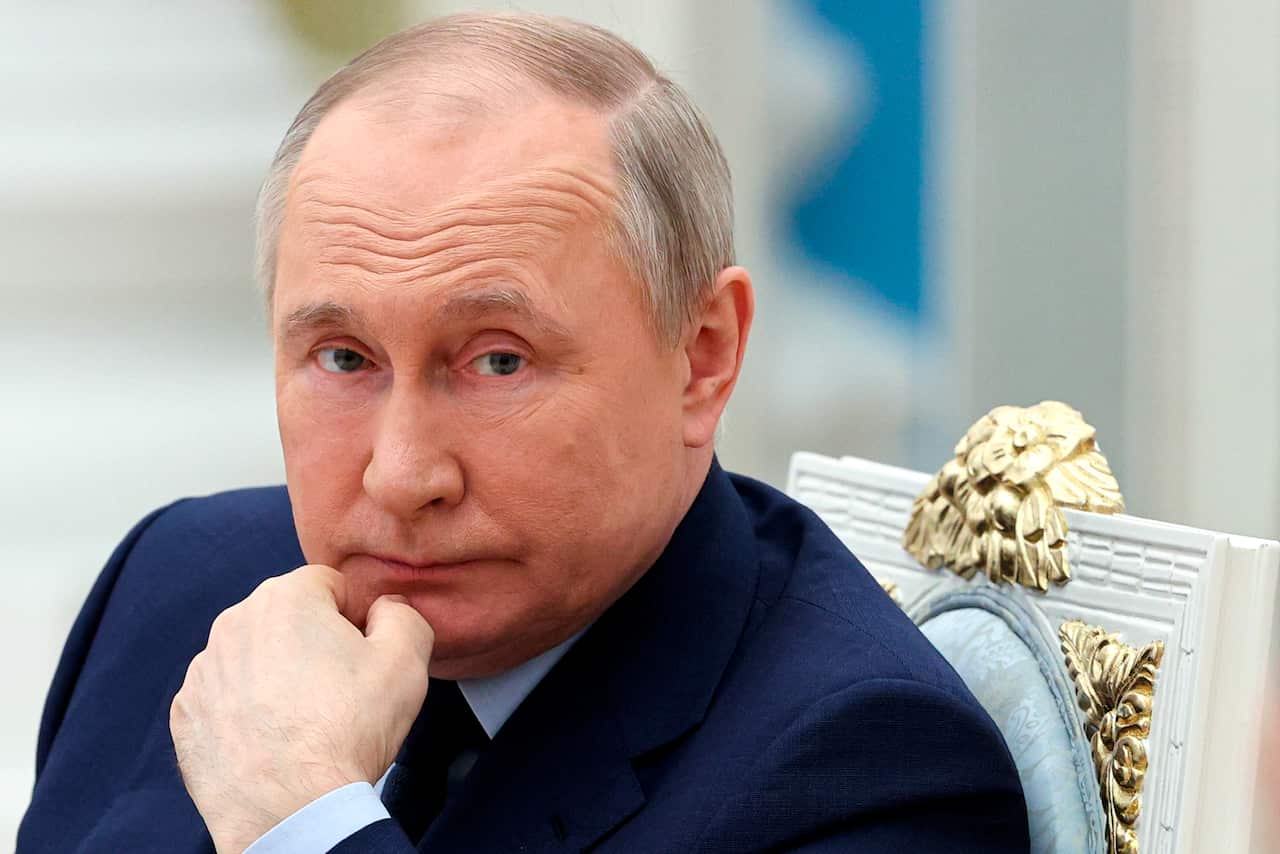 A man sitting down and touching his chin with his hand.