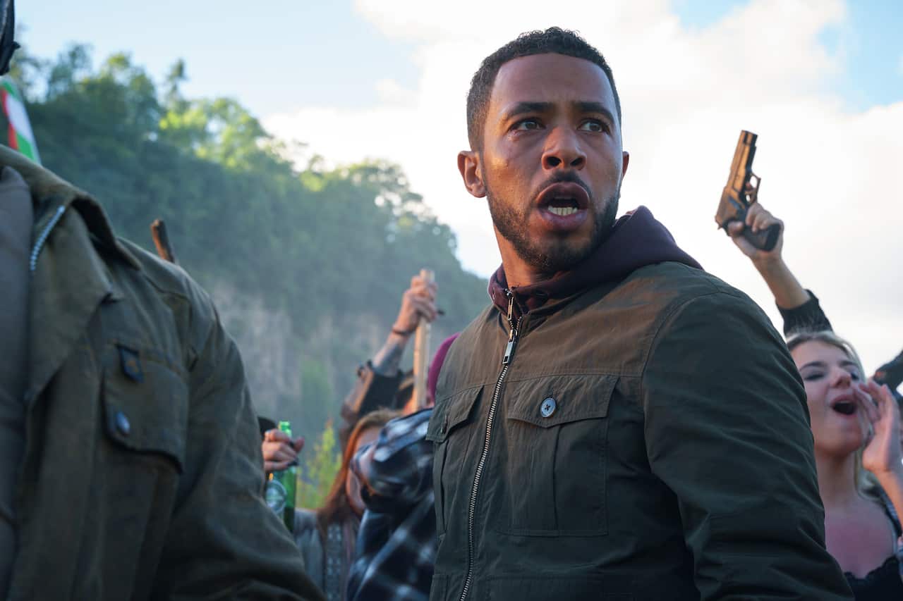 Actor Ukweli Roach stands among a riotous crowd looking stressed in UK series Wolf