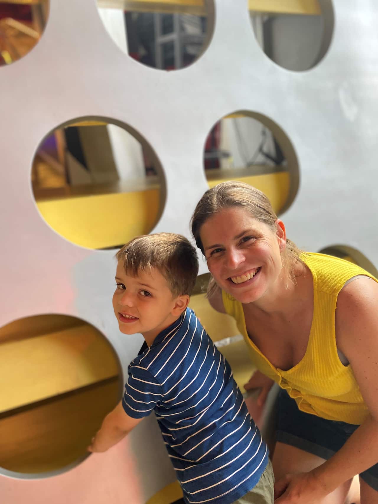 A mother and her young son smile together in a play centre.
