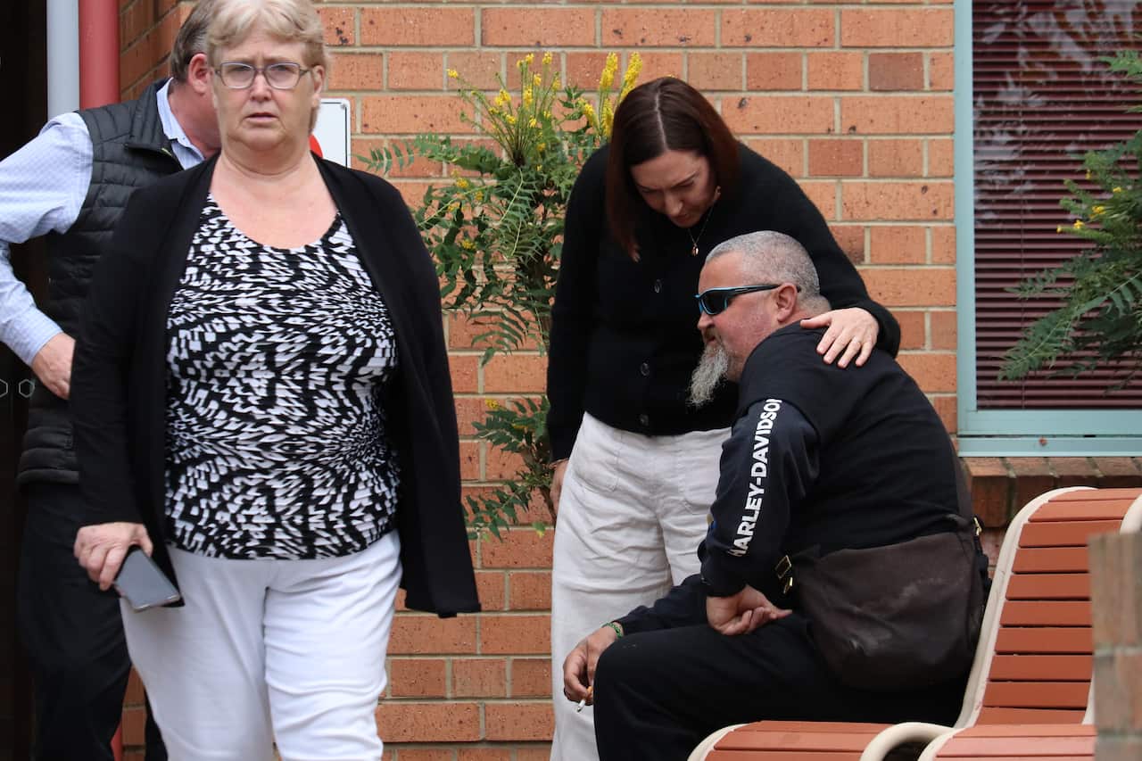 A man sitting on a bench is comforted by a woman.