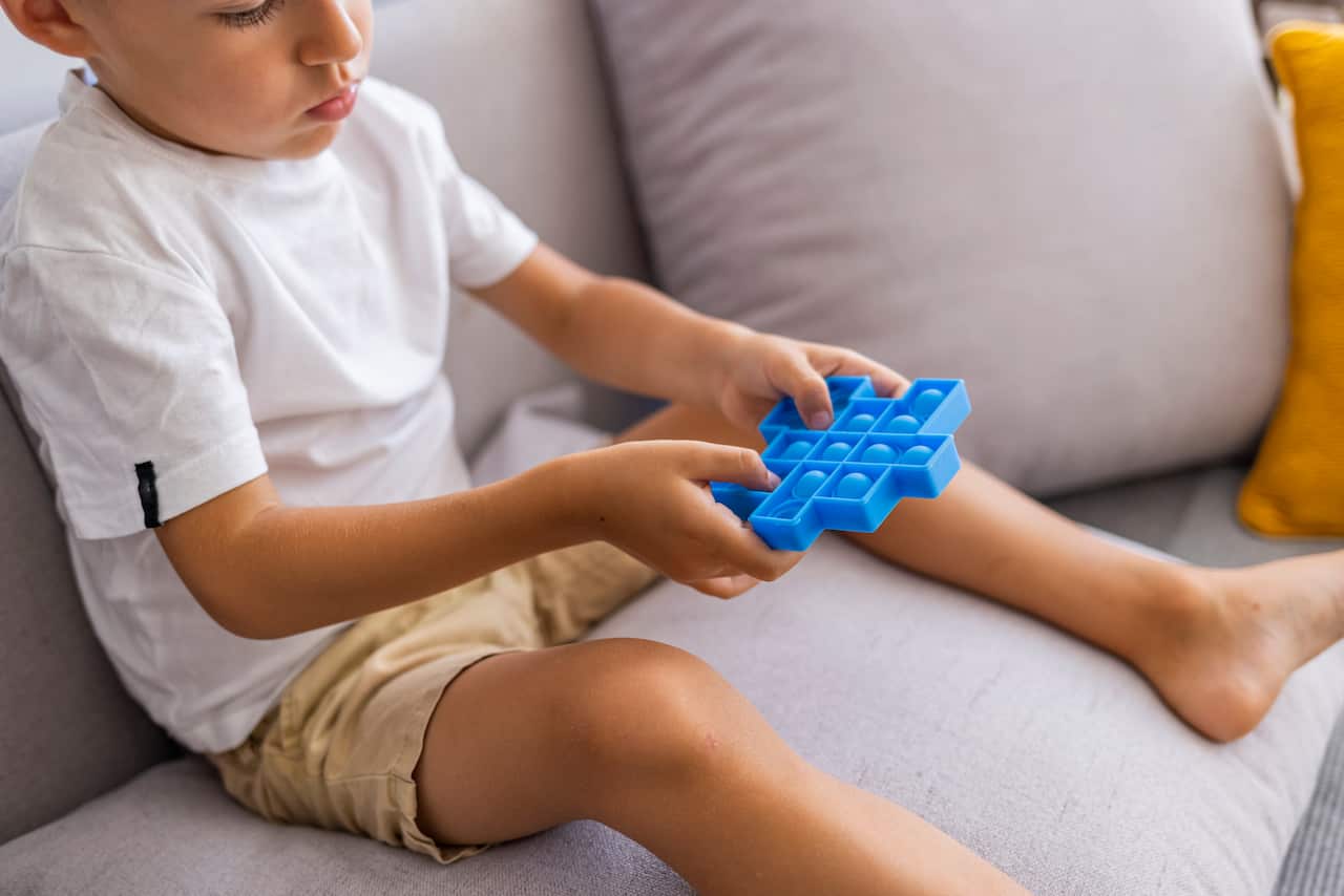 A young child playing with a pop-it style fidget toy.