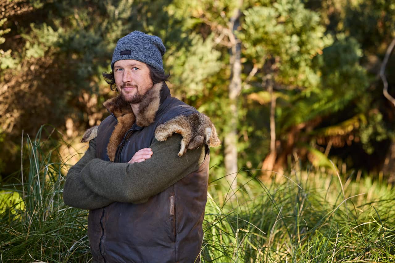 A man standing outside wearing outdoor gear and a beanie.