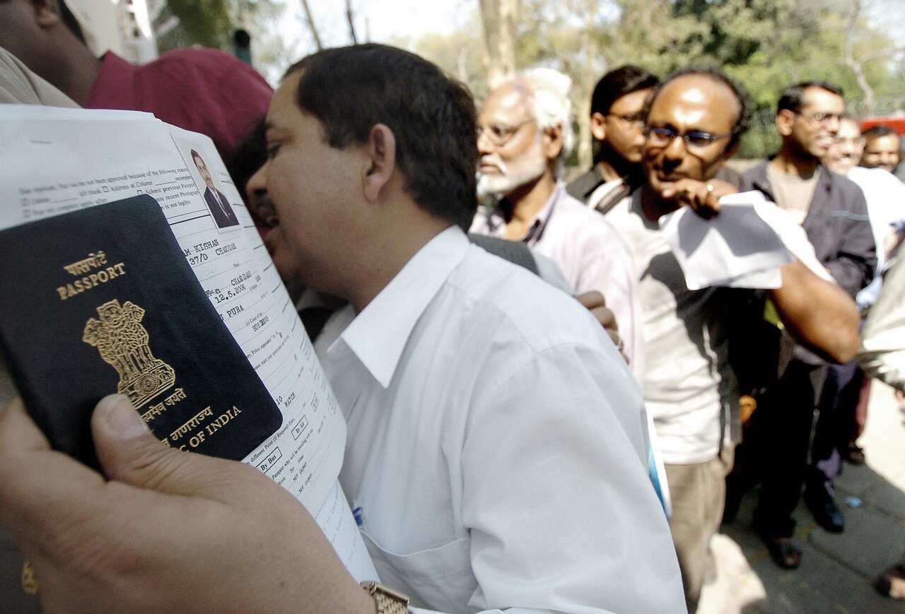 An Indian man holds his passport and vis