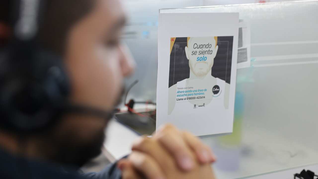 A man with headphones and a microphone with a poster reading "When you feel lonely" in the background. 