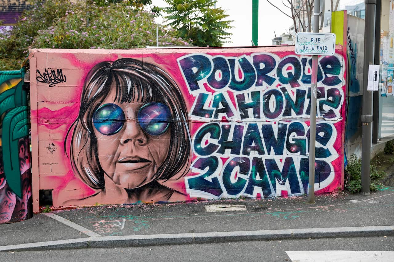 A colourful mural depicts Gisele Pelicot's face and a sentence reading "So that shame changes sides" in French. 