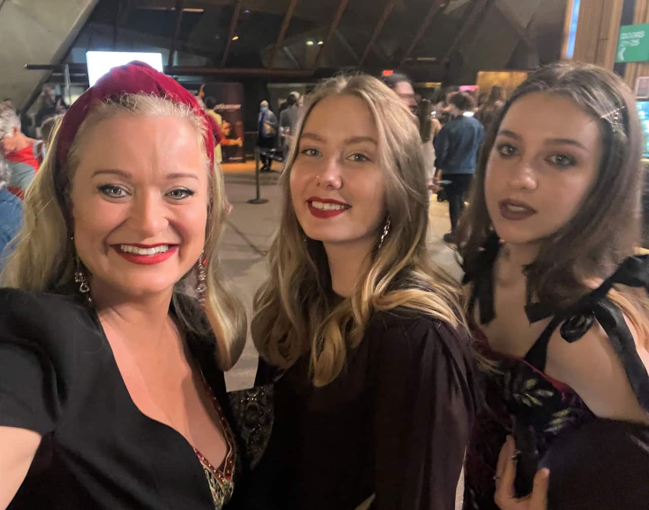 Three women smiling outside at night