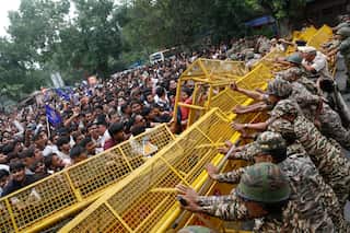 A crowd try to push through yellow barricades with police personnel trying to push from the opposite side