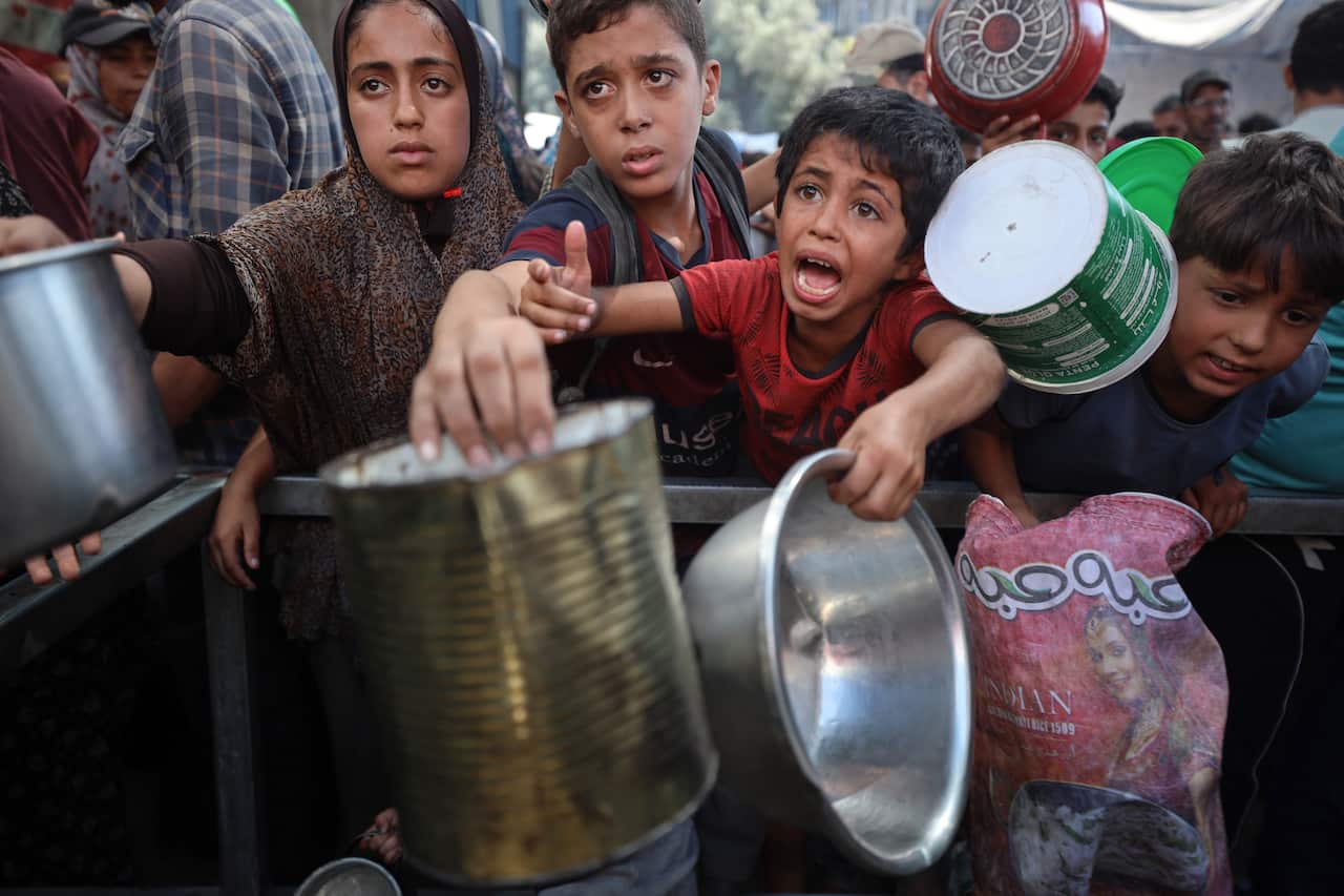 Children and mothers with buckets and bowls, in distress.