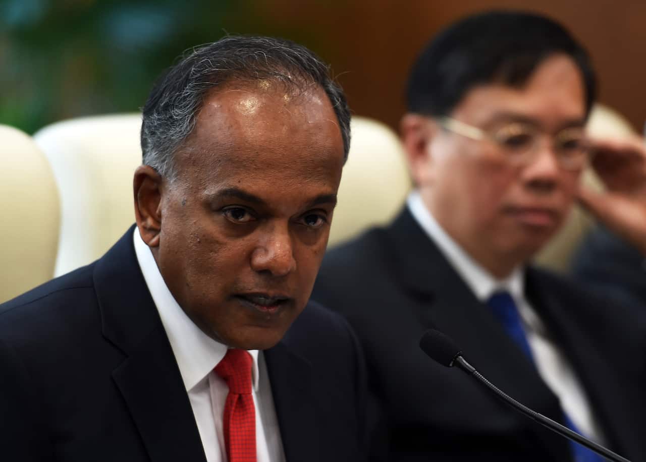 A man in suit and tie sitting behind a microphone