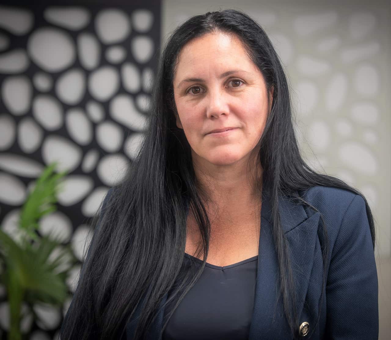Laura Cowell, TLC Australia CEO in a navy jacket leaning on an office partition.