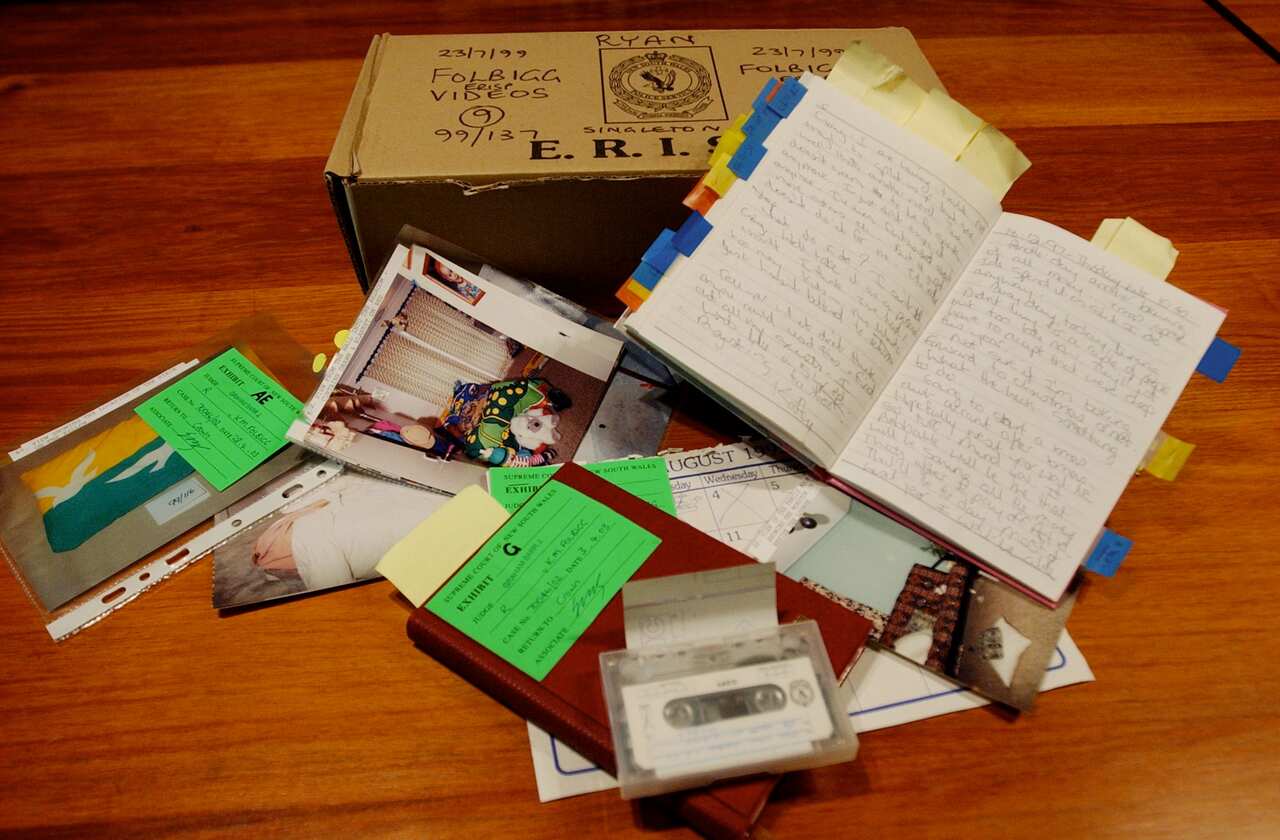 A box of evidence including a diary, photographs, a cassette tape, and a calendar