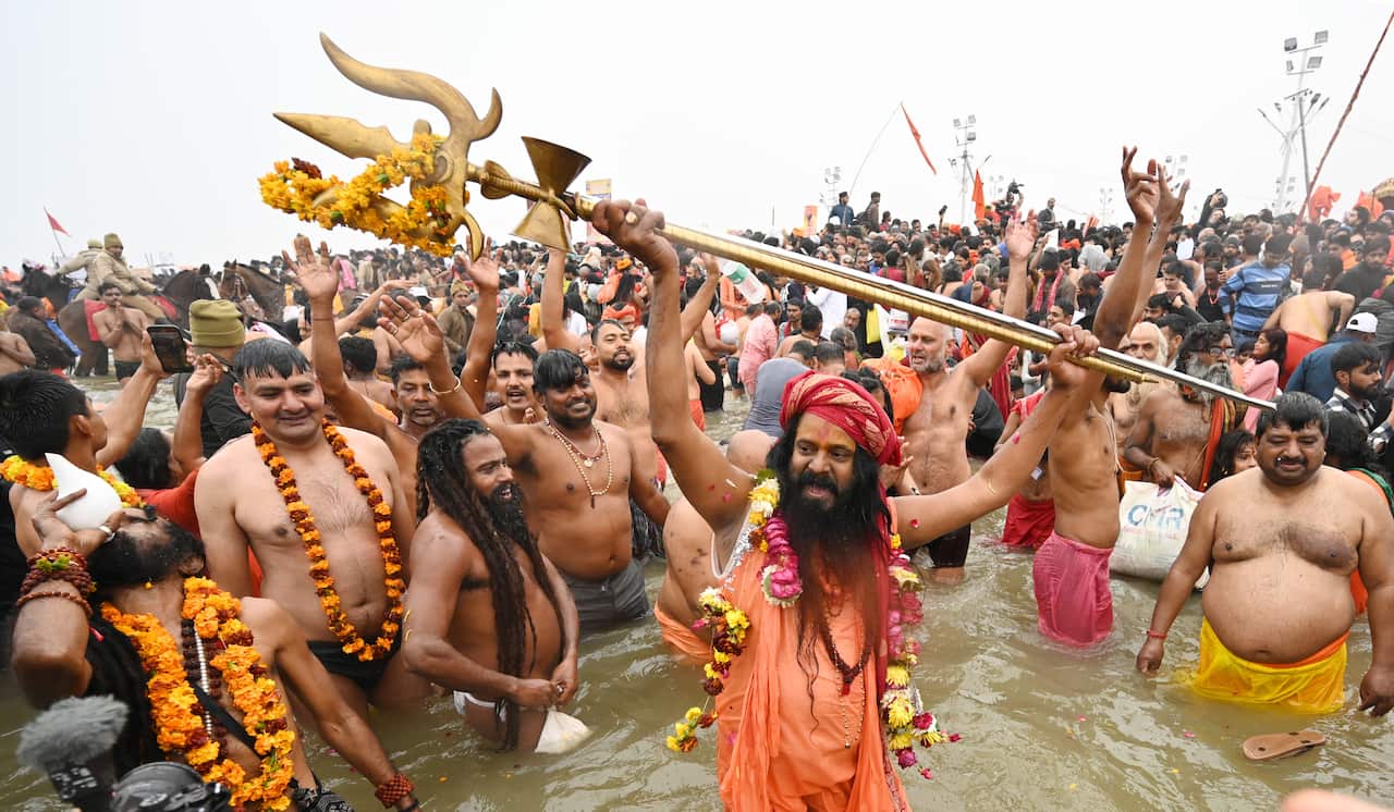 A crowd of people standing in a river, surrounding a man holding a trident.