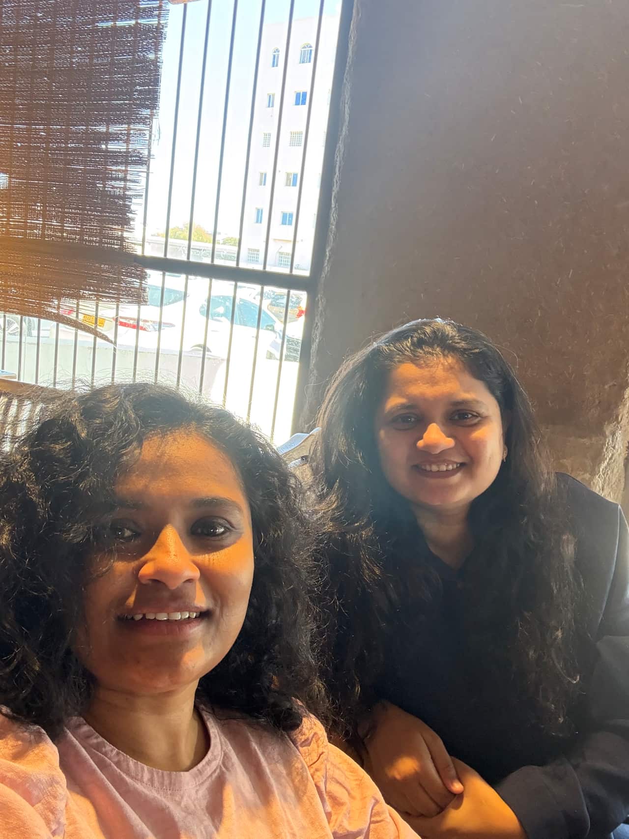 Two women in a room smile together as they look at the camera.