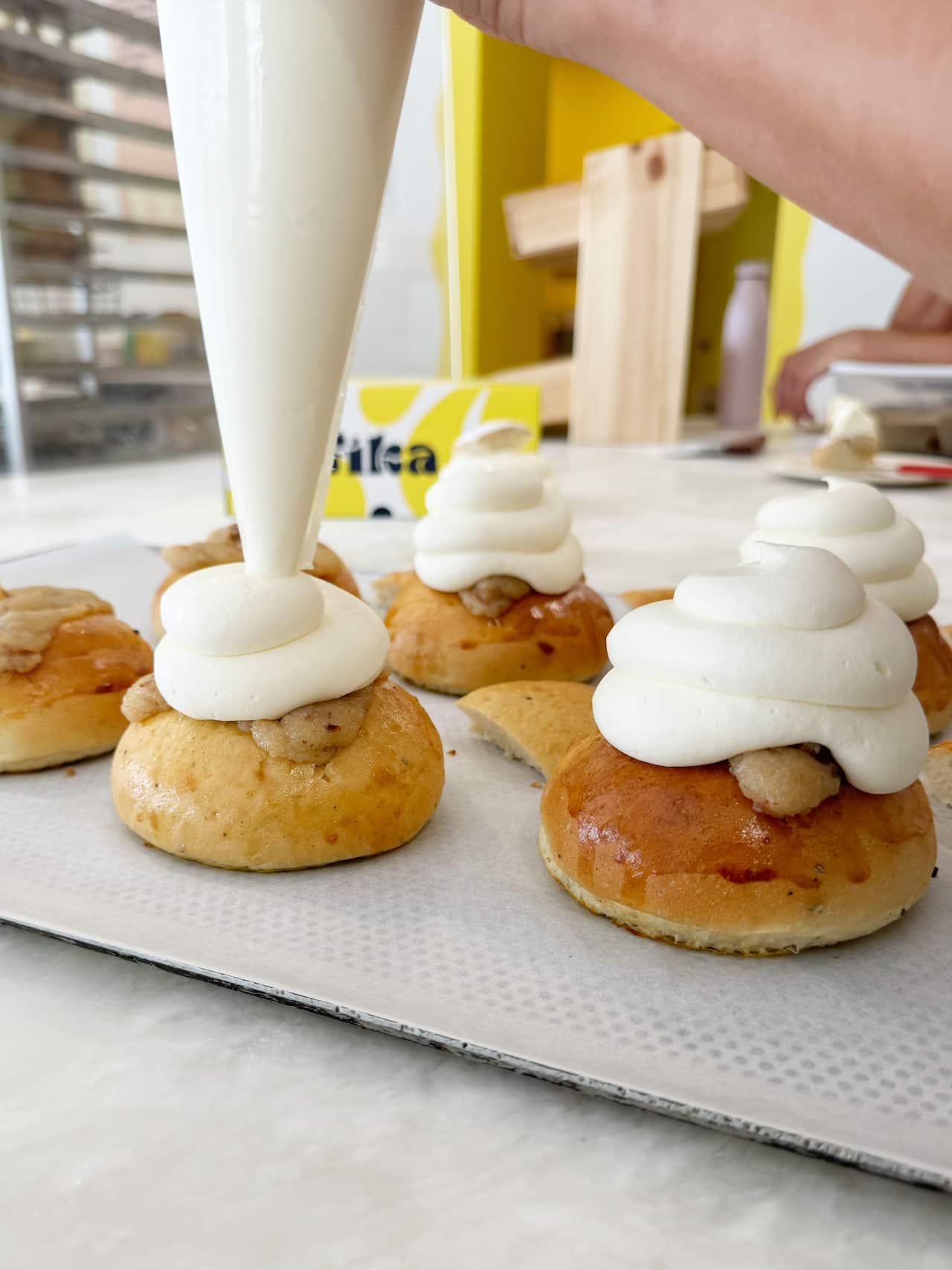 Cream piping bag piping cream onto bun.