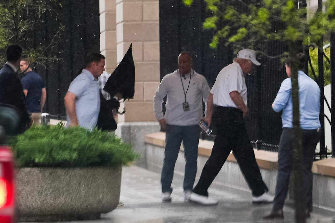 Group of older men enter building, US president wears white shirt and black pants