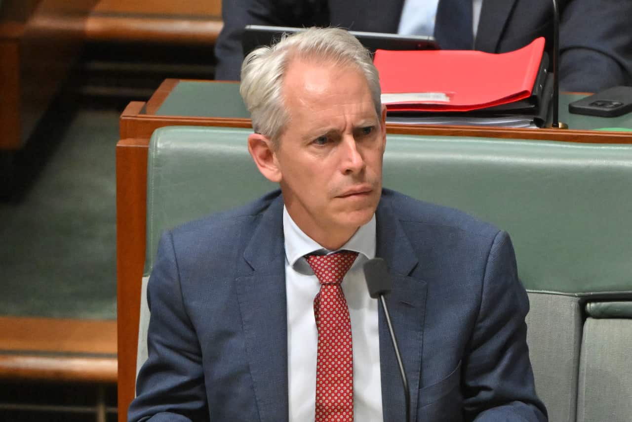 A grey haired man frowning 