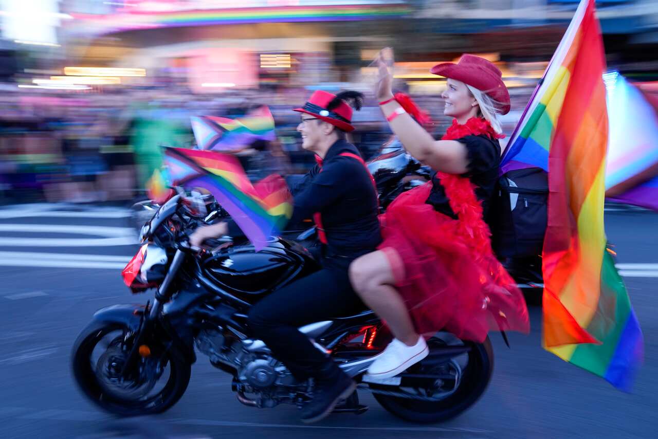 Two women on a motorbike with rainbow flags