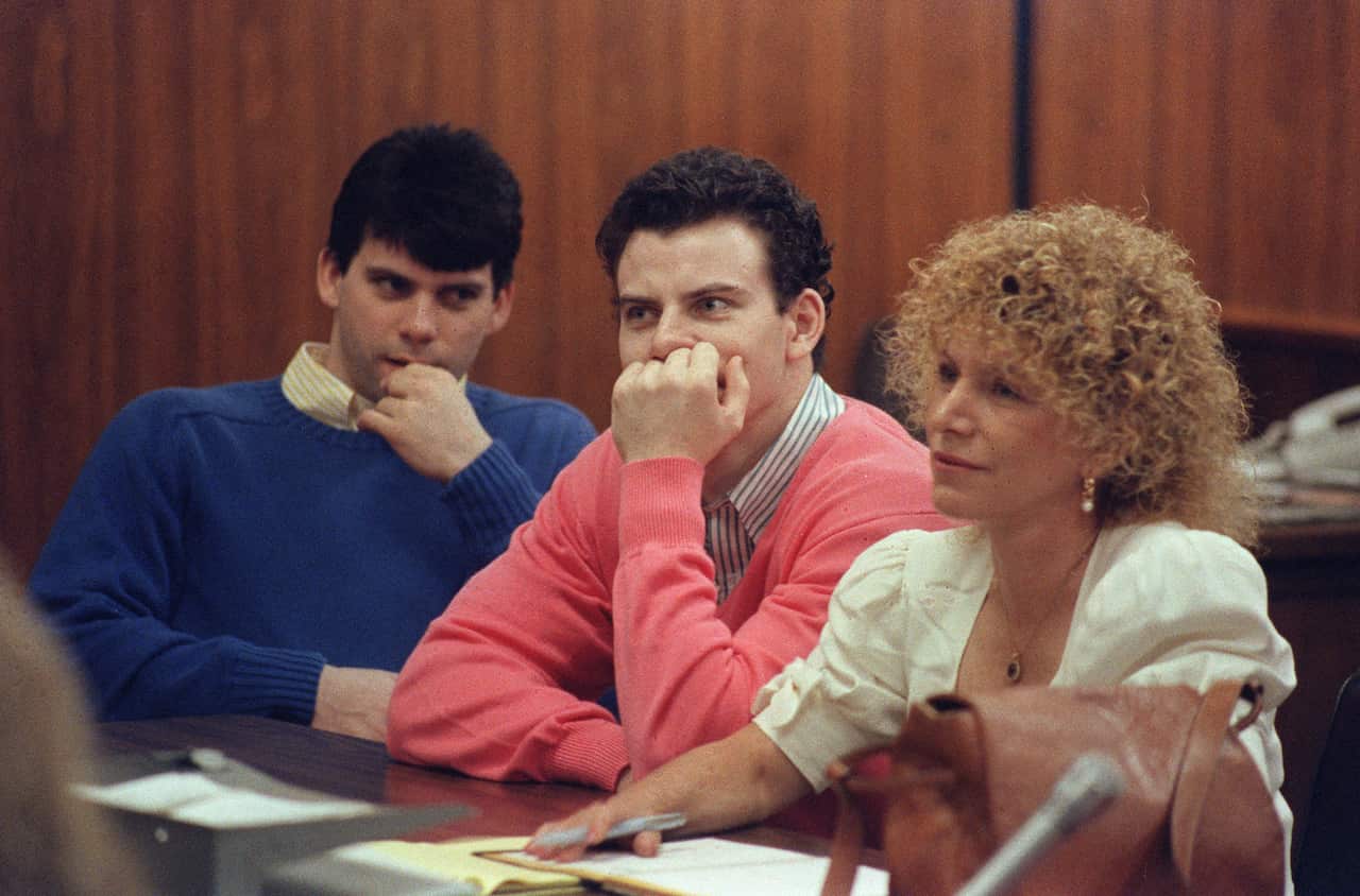 Lyle and Erik Menendez in court. One is wearing a collared shirt and a blue jumper and the other is wearing a collared shirt and a salmon-coloured jumper