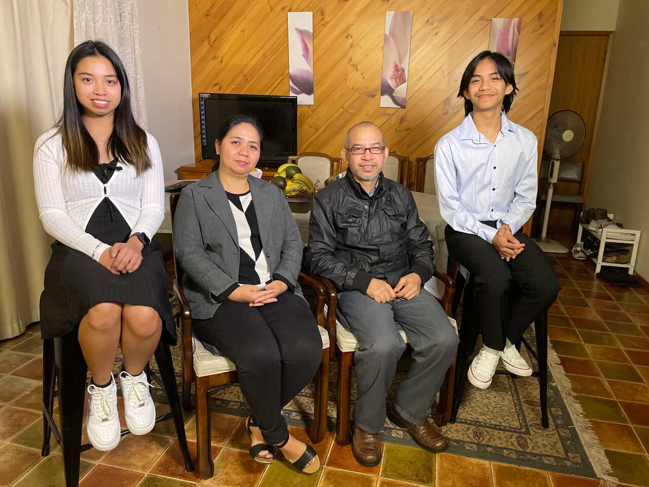 A Filipino family of four - two adults and two teenage children - sitting in their living room.