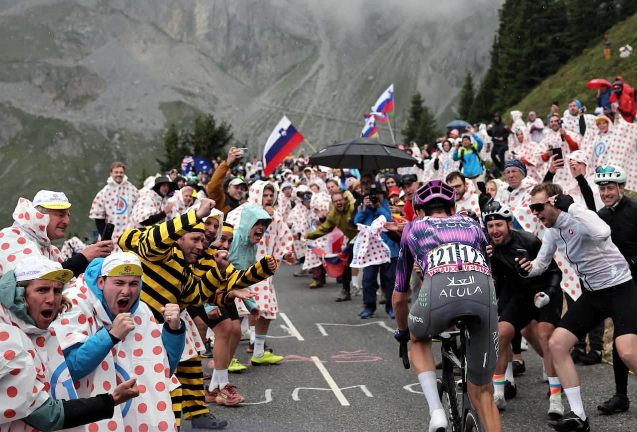 A cyclist riding through a mountain being cheered on by onlookers