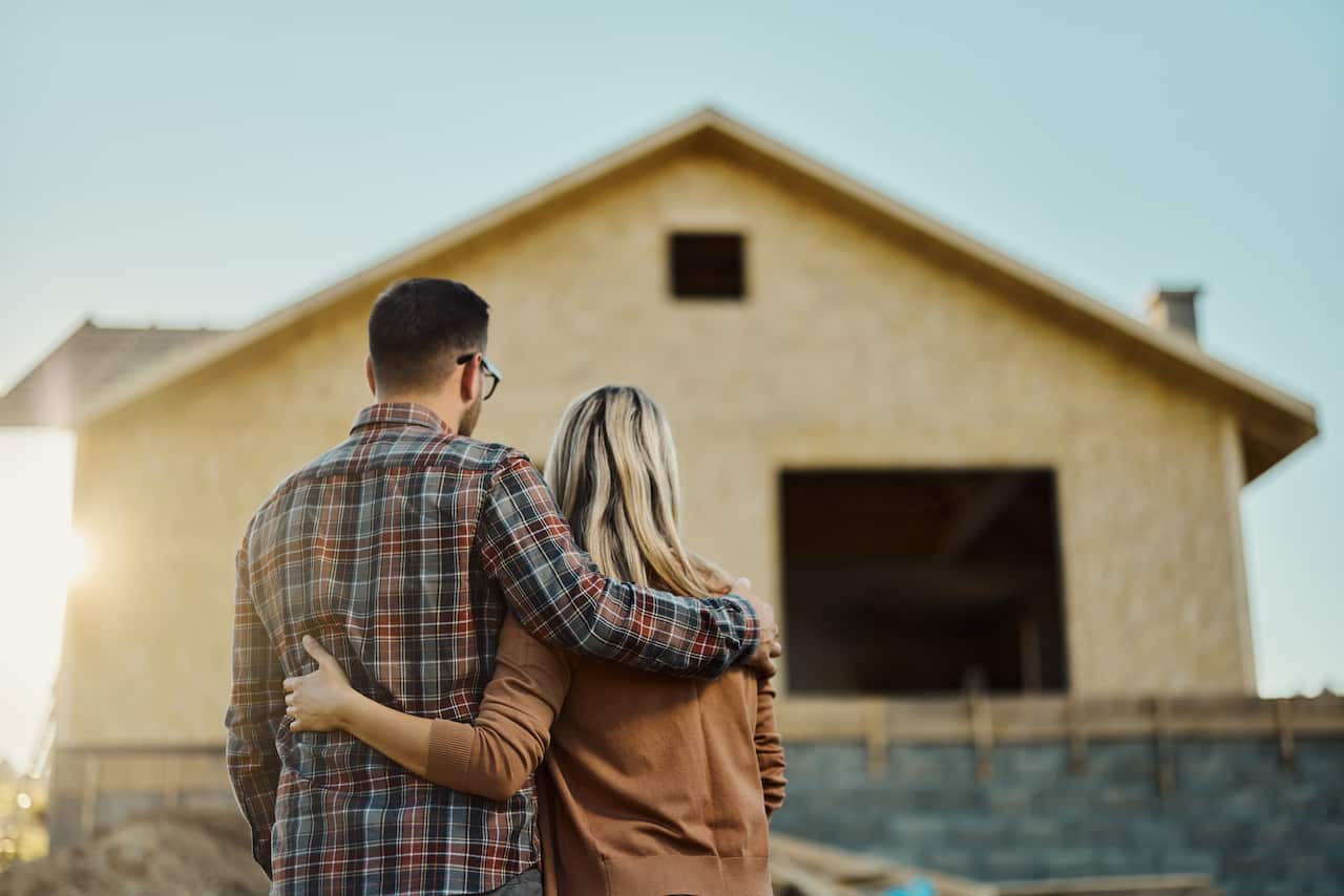 Rear view of an embraced couple looking at built structure from outside
