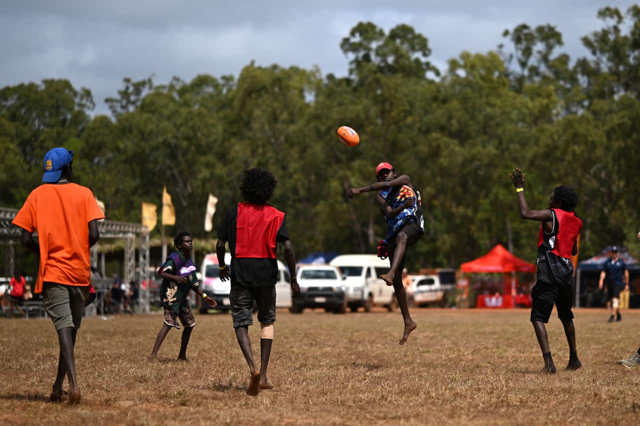 Young Indigenous men playing Aussie rules.
