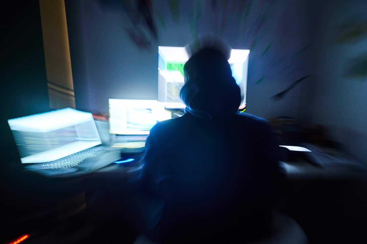 Fictitious html pages and hacker programs are shown on screens while a man has his hands on the keyboard