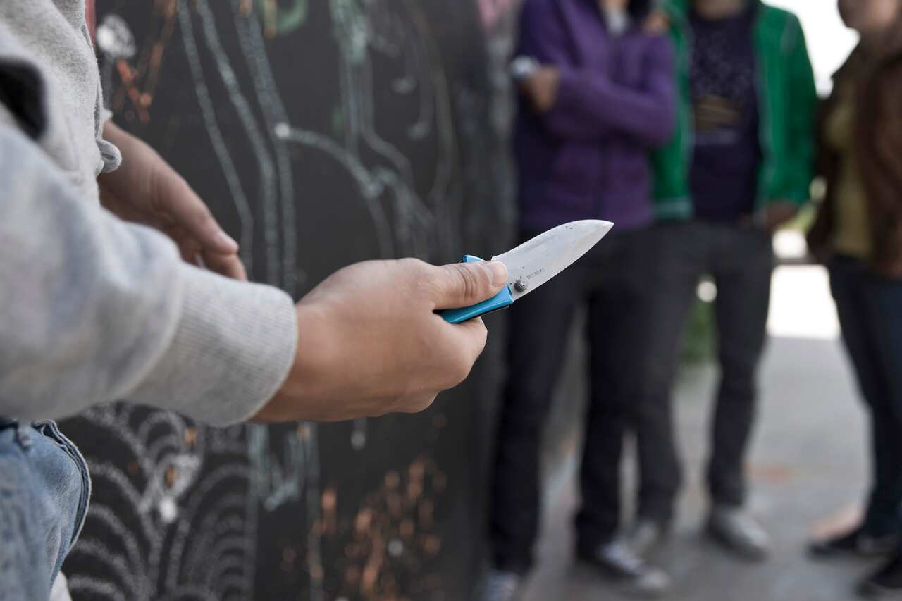 Adolescent threatening a group with a knife