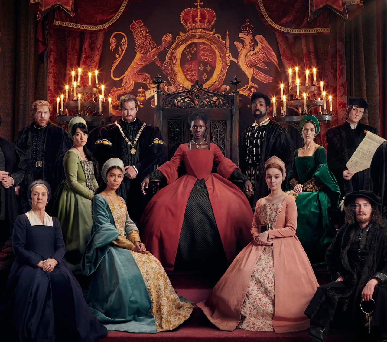 The cast of UK miniseries Anne Boleyn - Season 1 seated around Jodie Turner-Smith in a red gown and on a throne in the centre.