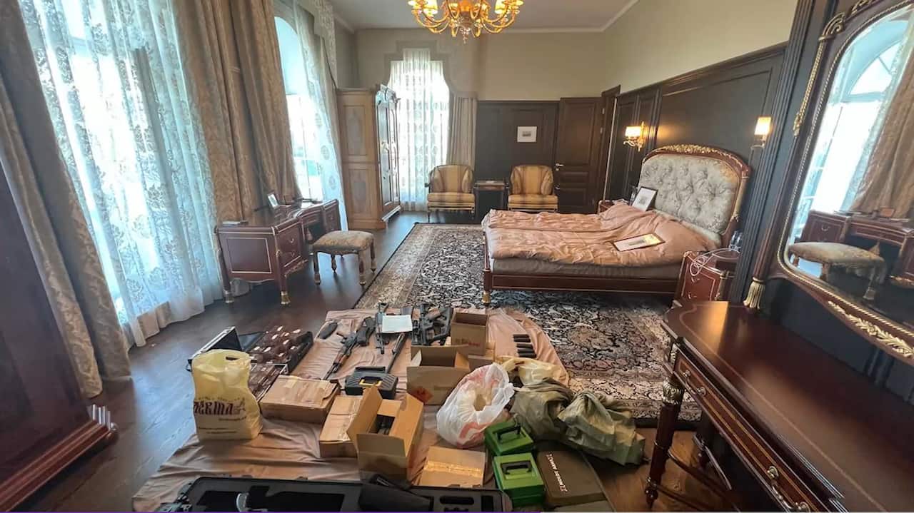 Guns and ammunition are laid out on the floor of a bedroom.