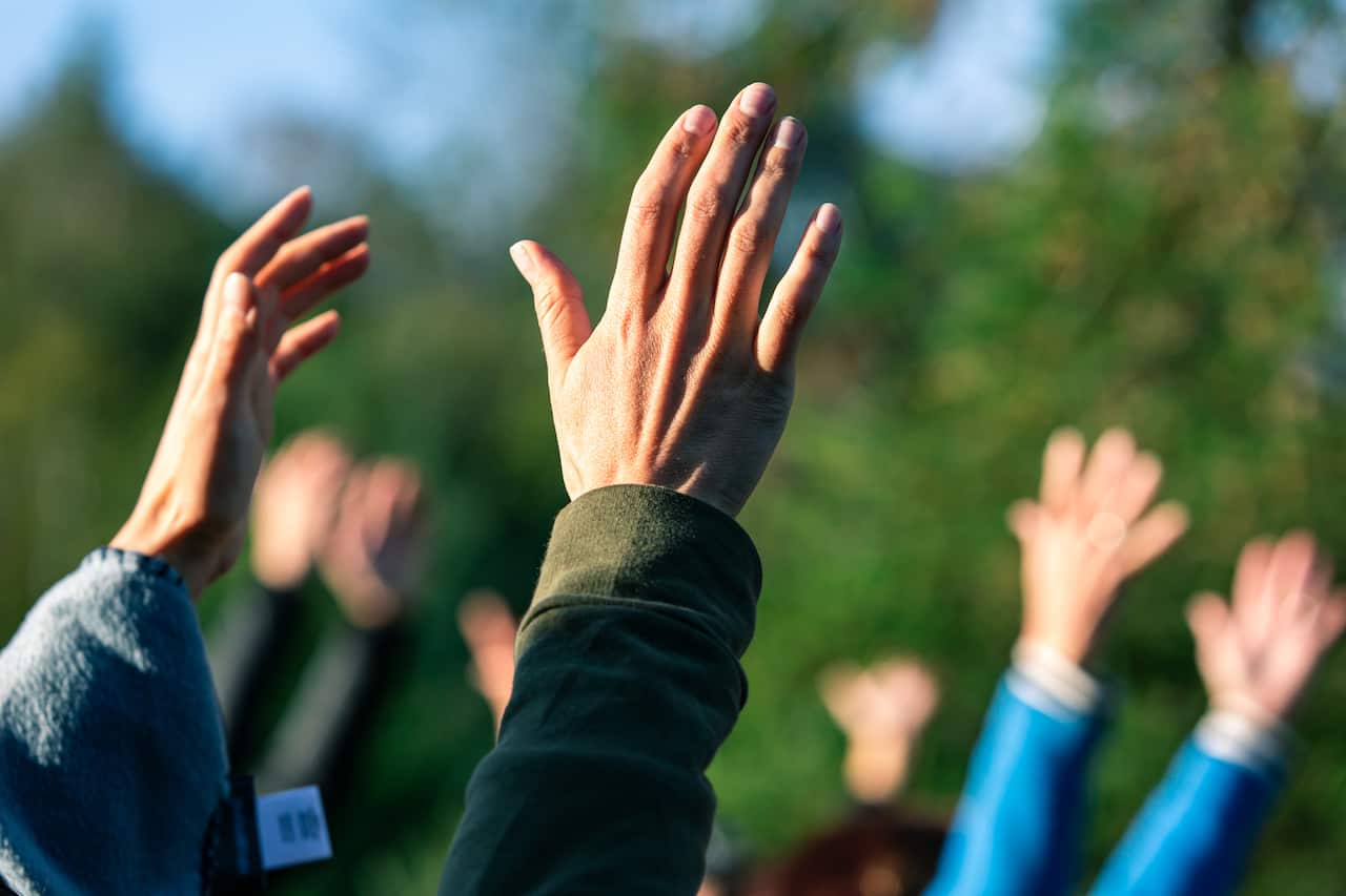 Group of people putting their hands up in the air.