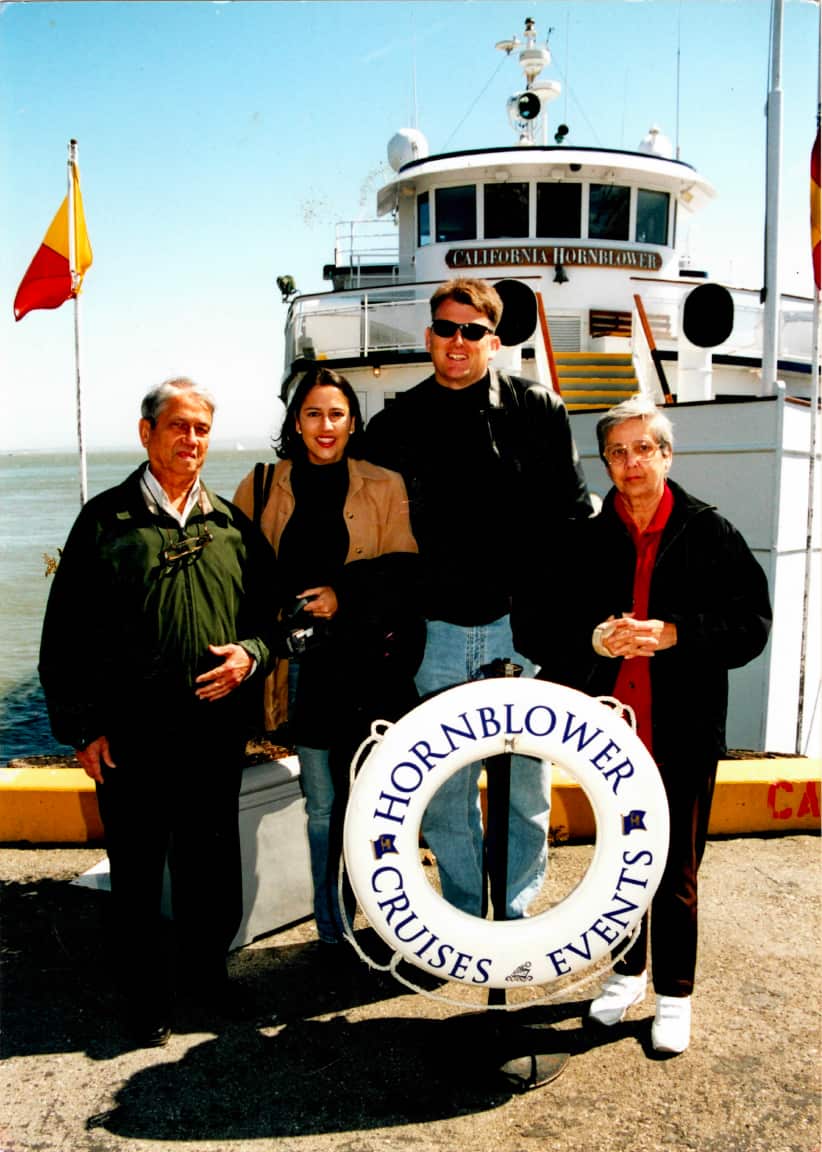 Alicia Young with her parents and her husband Jon on a pier with a boat behind them