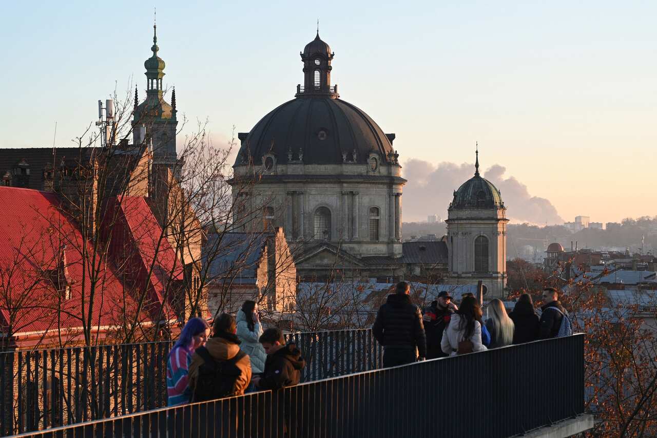 Residents in Lviv observe smoke billowing from a missile strike in the distance