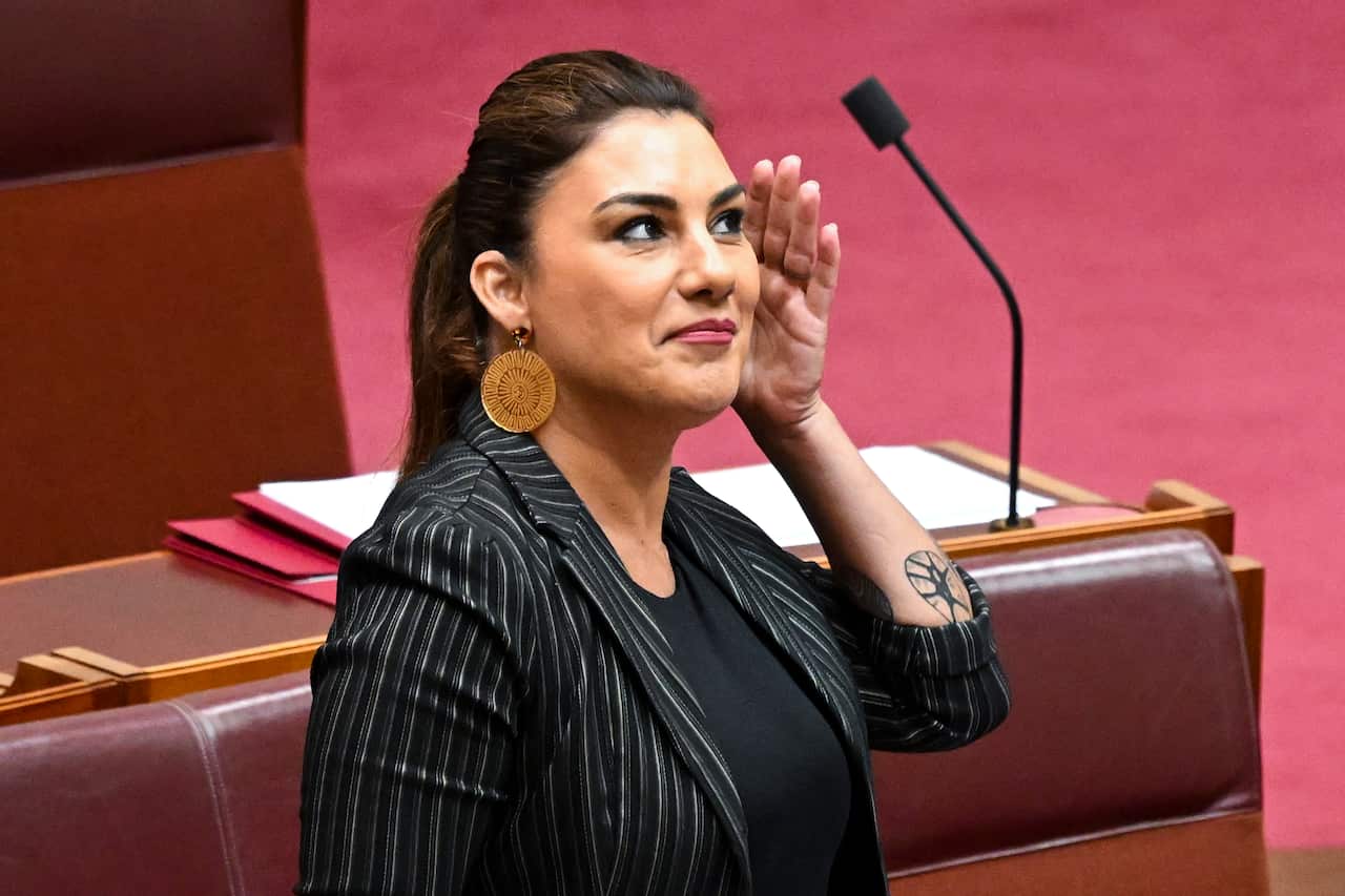 Woman cups her ear and smiles.