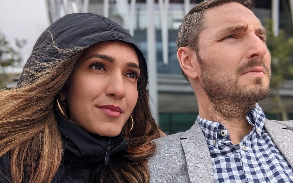 A woman in a black hoodie sitting next to a man in a checkered shirt