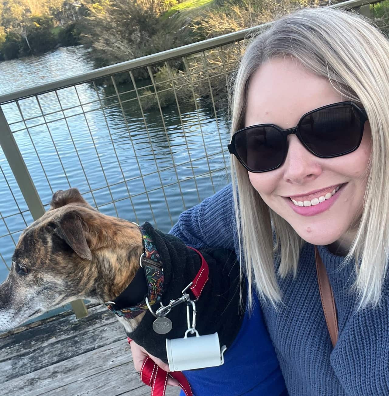 A woman posing next to a dog.