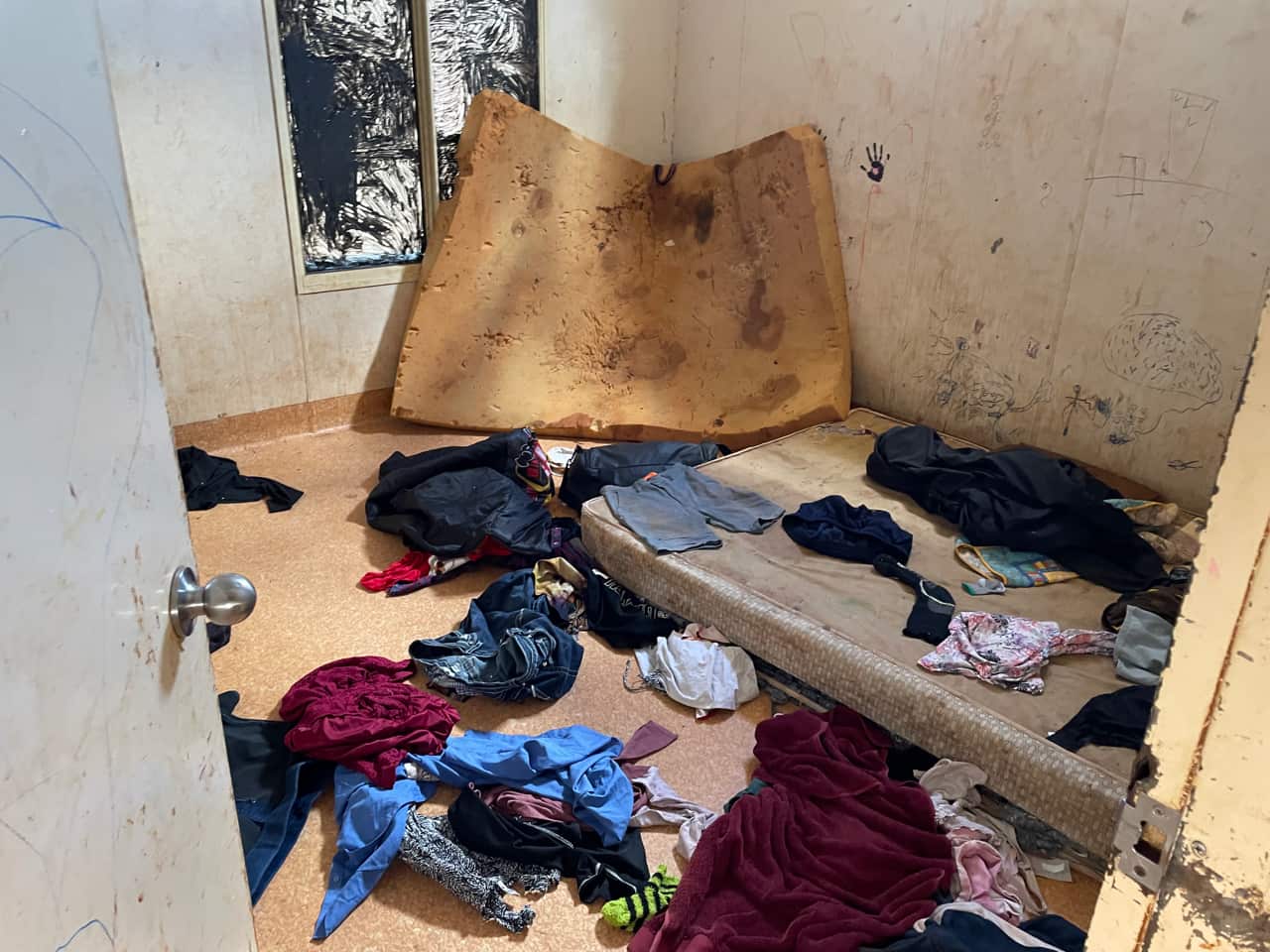 Two mattresses, clothes strewn in a room